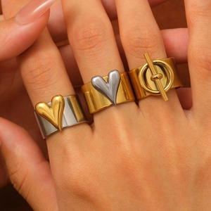 Close-up of wide wave texture rings in silver and gold contrast with heart details
