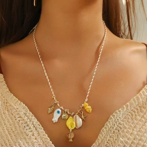 Dettaglio di una collana bohémien oceano con ciondoli a stella marina e conchiglia su modella