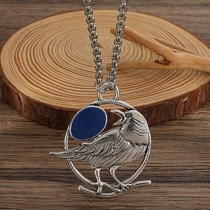 Macro del ciondolo corvo argento vintage con intarsio in smalto blu scuro su legno