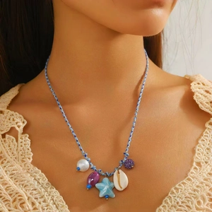 Dettaglio della collana bohémien con ciondolo a stella marina, conchiglia e perle colorate