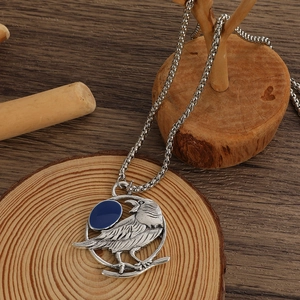 Dettaglio ravvicinato del ciondolo a colibrì vintage argento con pietra blu su legno