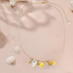 Dettaglio della collana boho oceano con stella marina dorata, conchiglia e perle blu