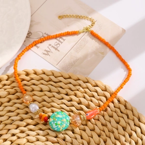 Dettaglio della collana di perline arancioni con pendente a forma di pesce in ceramica