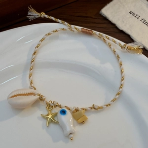 Dettaglio della collana in corda intrecciata stile oceano con conchiglia, stella e pesce
