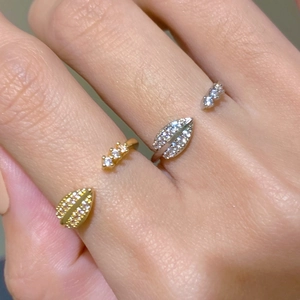 Macro shot of gold and silver leaf open rings with inlaid cubic zirconia on finger