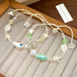 Bracciali estivi a tema oceano con pesci in ceramica e ciondoli a conchiglia su vassoio