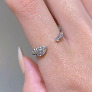 Macro shot of silver open ring with leaf design and white zircon stones on finger