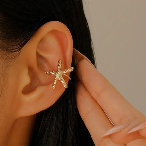 Detail of a golden starfish ear cuff with realistic texture on a female model's ear