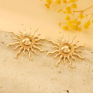Vista macro di orecchini a lobo a forma di sole dorato su espositore in pietra naturale