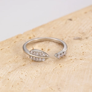 Macro shot of silver open ring with cubic zirconia leaf and arrow details on stone