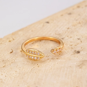 Detailed macro view of the gold-plated leaf ring with shimmering white zircon stones