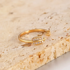 Macro detail of gold leaf open ring with sparkling pavé cubic zirconia on stone background