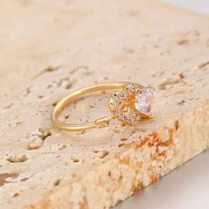 Macro detail of adjustable golden heart ring with arrow design and sparkling cubic zirconia