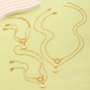 Golden sun and moon pendant necklace and bracelet set on a soft green background