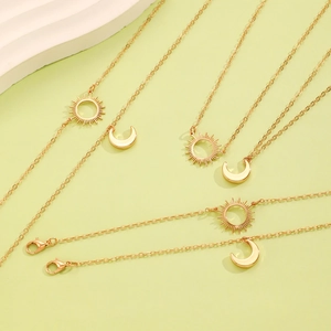 Golden sun and moon pendant necklace set on a minimalist light green background