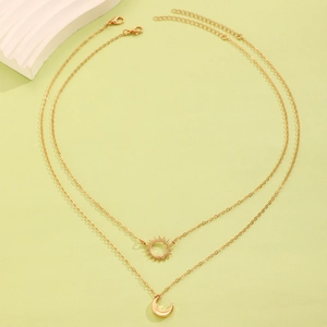 Detail shot of golden sun and moon pendant double-layer necklace set on green background