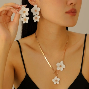 Détail d'une parure élégante à fleurs blanches avec chaîne serpent dorée et fermoir en T