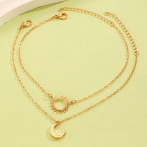 Detail of gold double-layered necklace featuring sunburst disk and crescent moon pendants