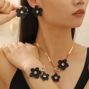 Détail d'un ensemble de bijoux fleurs noires avec chaînes dorées et fermoir à bascule