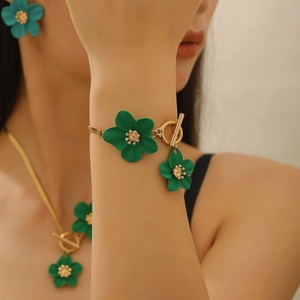 Gros plan d'un élégant bracelet fleur vert mat avec fermoir à bascule doré au poignet