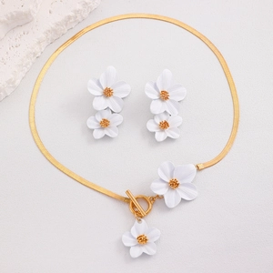 Gros plan sur la chaîne serpent dorée avec pendentifs fleurs blanches texturées