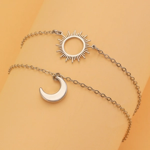 Close-up of silver sun and crescent moon pendants on fine chain jewelry set