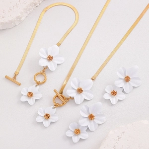 Vue détaillée d'une parure en or avec pendentifs fleurs blanches et fermoir à bascule OT