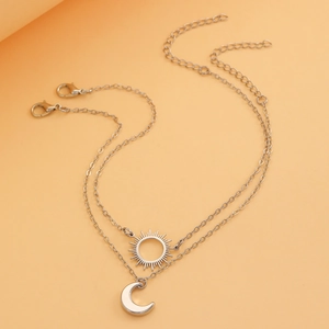 Detailed view of silver double-layer necklace with sun and crescent moon charms