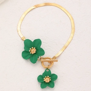 Gros plan détaillé d'un bracelet chaîne serpent doré avec fleurs vertes et fermoir en OT