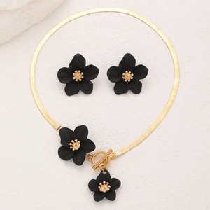 Détail du collier à chaîne serpent dorée et boucles d'oreilles fleurs noires mates