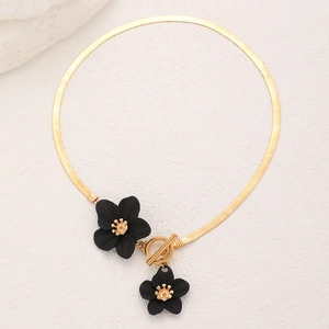 Détail du collier à chaîne serpent dorée avec pendentifs fleurs noires et fermoir à bascule