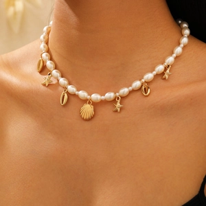 Gros plan d'un collier de perles avec pendentifs étoile de mer et coquillage dorés