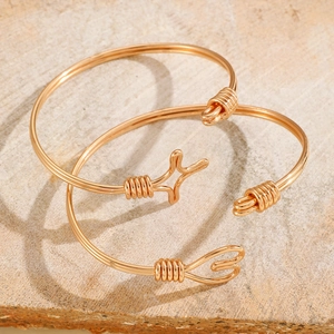 Minimalist gold woven open bangle set with heart and star charms on stone background