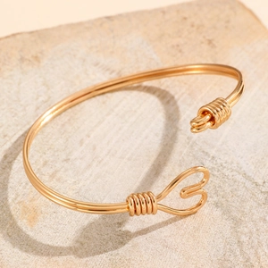Close-up of golden dual-line open bracelet with heart shape and wire-wrapped detail