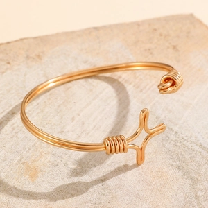 Close-up of golden wire-wrapped open bangle with a central star charm on stone base