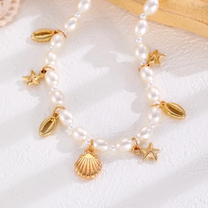 Détail macro d'un collier de perles avec pendentifs dorés en étoile de mer et coquillage