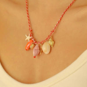 Dettaglio collana boho intrecciata con ciondoli in ceramica a conchiglia e stella marina