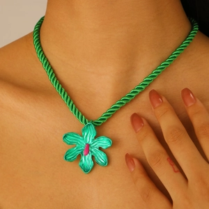 Detalle del collar de cordón de algodón verde con colgante de flor grande en el cuello