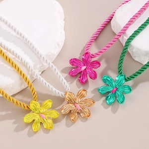Detailed view of colorful twisted cord necklaces with metallic flower pendants in four colors