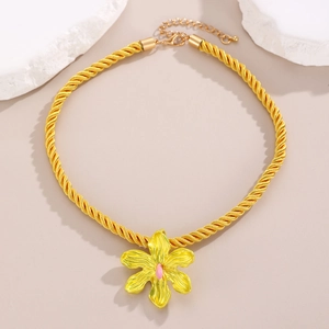 Macro detail of yellow floral pendant with pink stamen on braided cotton cord necklace