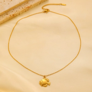 Detailed macro view of tropical fish pendant on gold stainless steel link chain