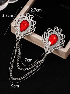 Detailed view of vintage crystal brooch with red pear-shaped gems and silver link chains