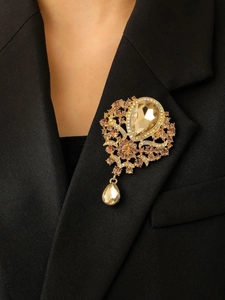 Detail of vintage champagne crystal brooch with teardrop pendant on black blazer