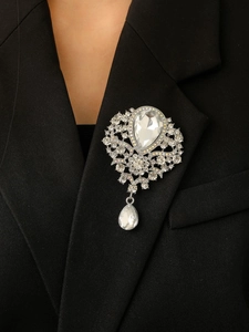 Macro detail of a baroque crystal brooch with a pear-shaped drop pendant on a suit