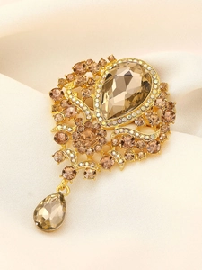 Close-up of vintage gold brooch with champagne crystals and pear-shaped drop pendant