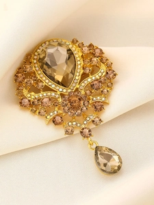 Macro detail of vintage gold brooch with champagne crystals and teardrop pendant
