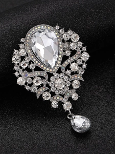 Detailed close-up of a silver brooch with crystal teardrop stones and rhinestone accents
