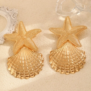 Golden starfish and seashell drop earrings on a sandy beach themed background