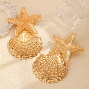 Macro detail of gold sea star and scallop shell earrings with a high-polished finish