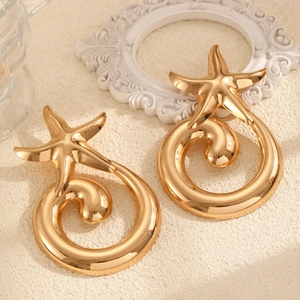 Detailed view of large gold-tone starfish earrings with spiral hoops and a polished finish